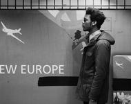 Schwarzer Mann vor einem lebensgroßen Plakat. "New Europe" Foto von Johny Pitts in Schwarz-Weiß