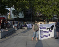 Left a few people on a stone bench, giving a speech. In the Backround loudspeeker on a bike trailer and a banner. In front two people holding a banner, too: Mein Körper, meine Entscheidung.