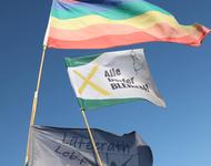 Verschiedene Flaggen im Wind, unter anderem Alle Dörfer bleiben, Lützerath lebt und Pride Flage
