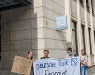 Menschen protestieren mit einem Banner mit der Aufschrift Deutsche Bank finanziert Klimakatastrophe und einem Schild mit der Aufschrift Pakistan is our story vor der Deutschen Bank Filiale in Freiburg.