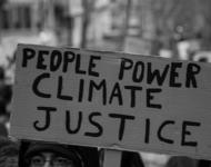 Eine Person, die ein Schild mit der Aufschrift "People Power - Climate Justice" hochhält