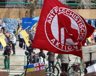 Eine rote Flagge: Antifaschistische Aktion. Dahinter auf dem Platz der Alten Synagoge sind Baden-Württembergflaggen und die Farben der AfD auszumachen