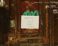 Eine verranzte Holztür zerkratzt mit Graffitis und einem Zettel: EXPOSED Super 8 Filmfestival aka filmclub