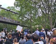 Solidaritätskundgebung in Paris, Nanterre für Nahel am 29 Juni 2023: Menschen stehen unter einer Brücke mit Schildern und blicken zu einer Person die vor Bäumen eine Rede hält