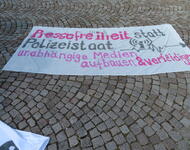 Ein Transpi liegt auf Kopfsteinpflaster. Darauf steh in pink und schwarz: Pressefreiheit statt Polizeistaat. unabhängige Medien aufbauen & verteidigen