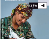 Eine Frau in der Uniform der kurdischen Frauenarmee YPJ füttert eine weiße Taube und lächelt dabei