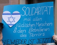Ein blaues Plakat mit einem weißen Herz mit Davidstern und zwei blauen Streifen: Solidarität mit allen jüdischen Menschen & den Betroffenen des Terrors - Nie wieder ist jetzt!