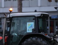 Ein Traktor in der Nahaufnahme. An der Seite klebt ein Plakat auf dem steht: "Landwirtschaft ist bunt nicht braun".