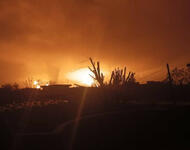 Explosion über einer ländlichen Region - die Flammen erhellen den Himmel, vereinzelt heben sich nur Gewächse und Häuser als Silhouetten ab