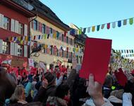 Das Bild zeigt eine große Menschenmenge im Zentrum der Stadt Waldshut, die rote Karten nach oben halten.
