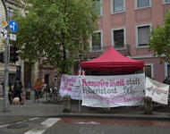 Ein roter Pavillion steht im Regen an der Straßenseite. Es sind verschiedene Transparente die zur Verteidigung der Pressefreiheit aufrufen angebracht und ein Banner von Radio Dreyeckland.