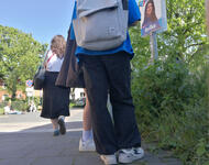 Reisende stehen und sitzen am Bahnsteig in Neu-Edingen/Friedrichsfeld herum. Die Sonne scheint, ein Wahlplakat ist an einem Pfosten zu sehen