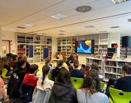 Gespräch an Schule Sitzreihen von Schüler*innen von hinten mit Carmen Spitta auf dem Podium