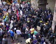 Blockade gegen die Piusbrüder 2015 in Freiburg - einige Demonstrierende sitzen noch vor der Polizeikette, viele andere stehen; viele Fahnen und Schilder